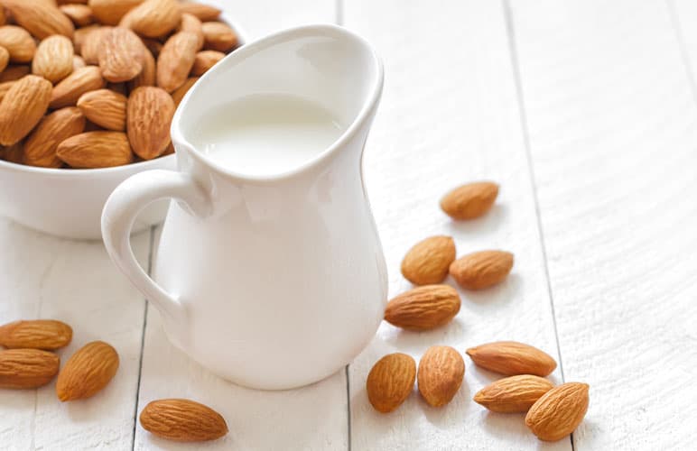 photo of a jug of milk with almonds nearby